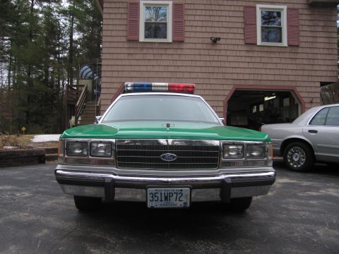 1991 Ford LTD Crown Victoria - Front view of a green-hooded sedan with a Ford oval grille, chrome bumper, light bar, and a New Hampshire 351WP72 plate.