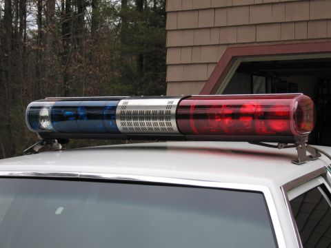 1991 Ford LTD Crown Victoria - Close-up of a long police roof light bar with red, clear and blue lenses mounted on a vehicle roof outdoors.