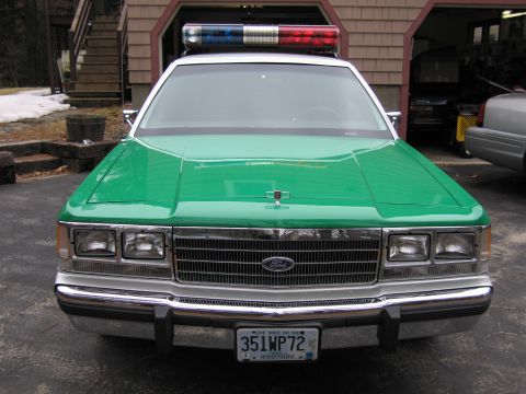 1991 Ford LTD Crown Victoria - Head-on view of a green Ford sedan's front grille and quad headlights, with a New Hampshire plate reading 351WP72.