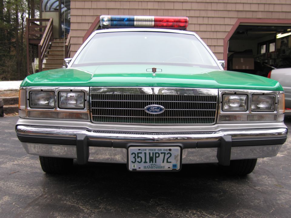 Front grille and headlights of green and white Ford police sedan, plate 351WP72