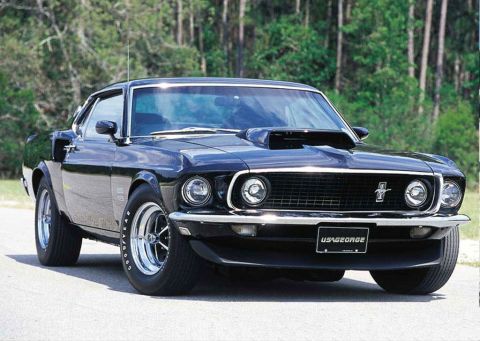 1973 Ford Ranchero - A black 1969 Ford Mustang with a prominent hood scoop is shown from a three-quarter front angle.
