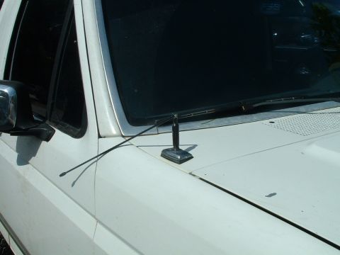 1995 Ford Bronco - Close-up view of the hood of a white SUV, showing the antenna and windshield wipers.