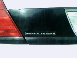 2001 Ford Crown Victoria - Close-up of the rear of a black Ford Crown Victoria Police Interceptor, showing the 'Police Interceptor' badge.