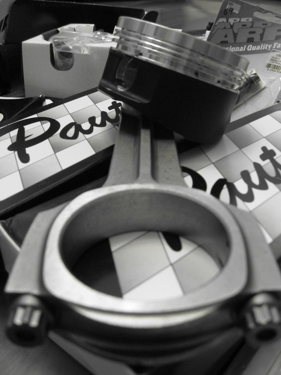 Piston and connecting rod on checkered background with 'Paut' text