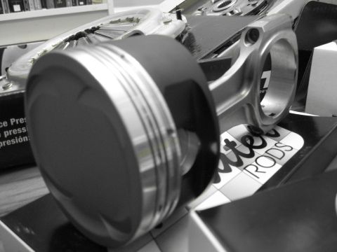1994 Ford Probe - Close-up of engine parts, including a piston and connecting rod, with text visible on packaging.