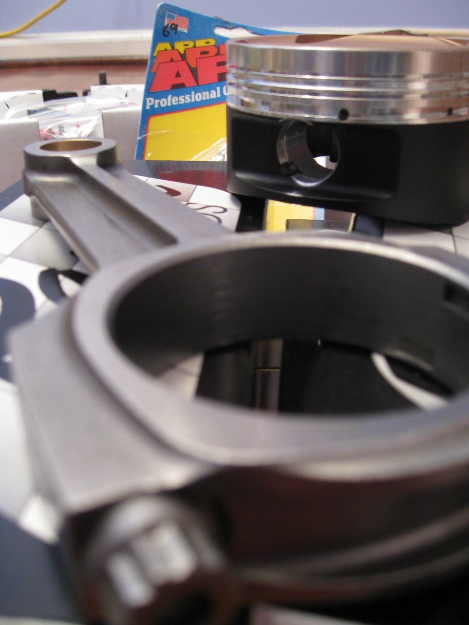 Connecting rod and piston with an AP Professional Gasket box in the background