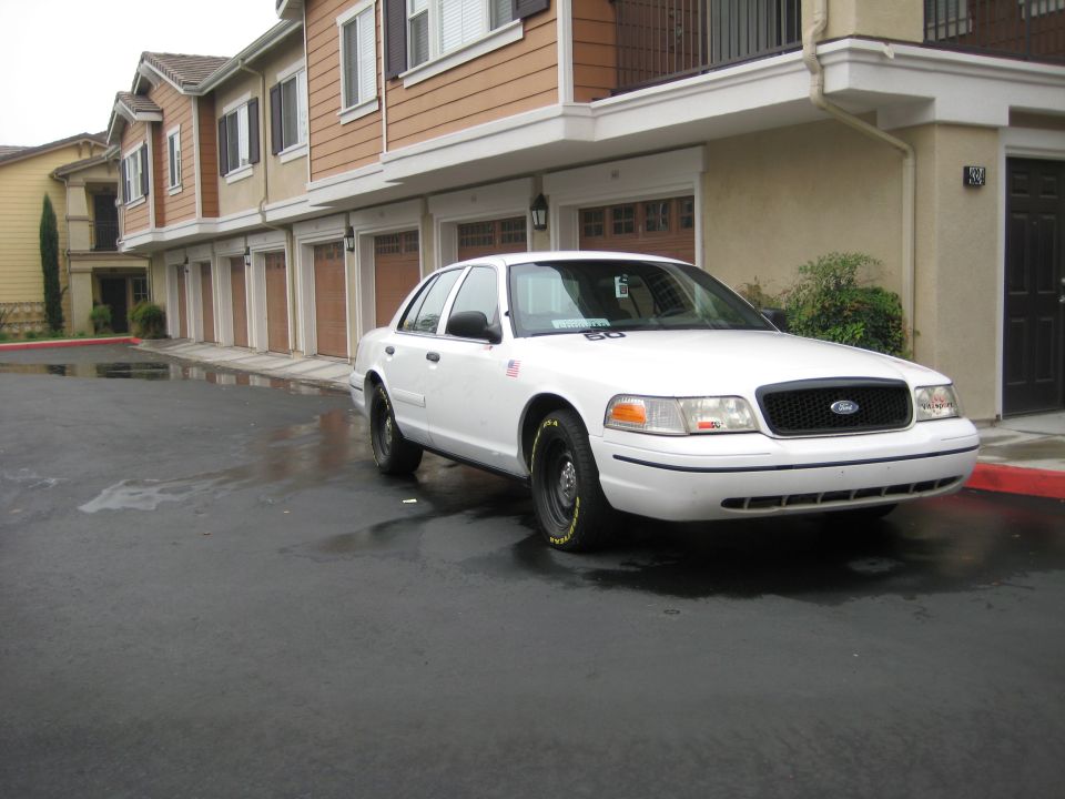 White 2001 Ford Crown Victoria parked on wet asphalt, front 3/4 view
