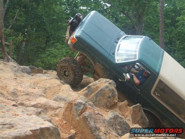 Off-road vehicle climbing steep rocky terrain. Driver is visible inside