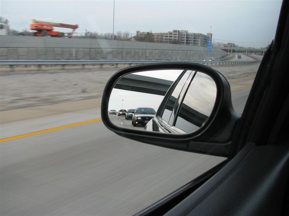 Cars on highway seen in side mirror reflection