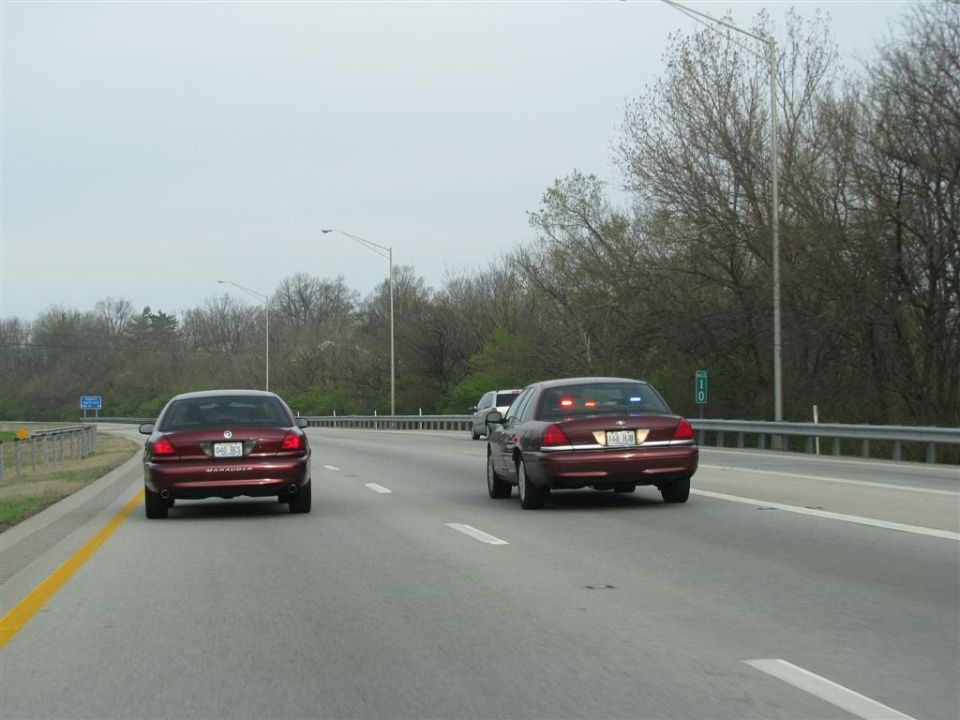Two maroon 2003 Mercury Marauders on highway, one with lights on