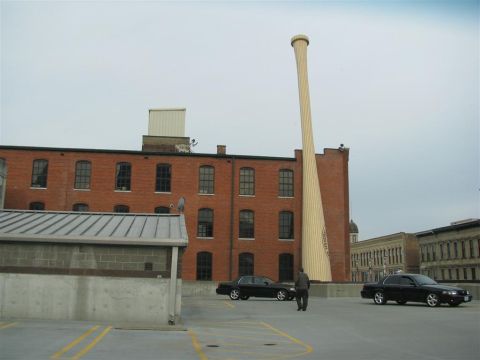 2003 Mercury Marauder - A person stands between two sedans on a rooftop parking lot, with a massive baseball bat sculpture and brick building in the background.