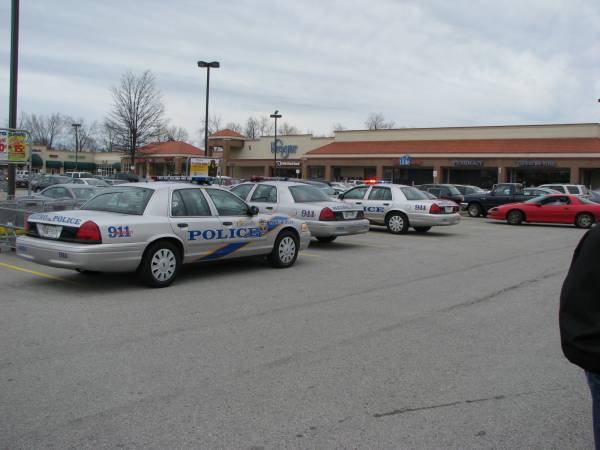 Three white police Crown Victoria cruisers in a shopping center lot