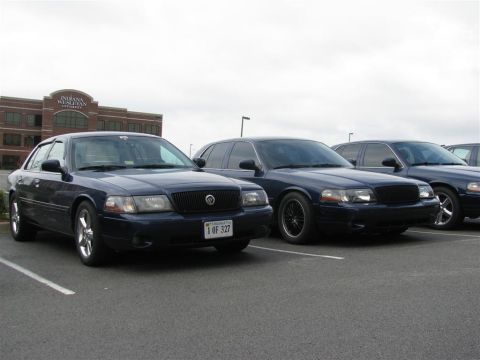 2003 Mercury Marauder - Three dark blue sedans, identified as 2003 Mercury Marauders, are parked in a lot with a building in the background.