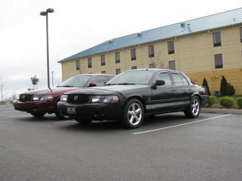 2003 Mercury Marauder - Two Mercury Marauders are parked side-by-side in a parking lot in front of a hotel.