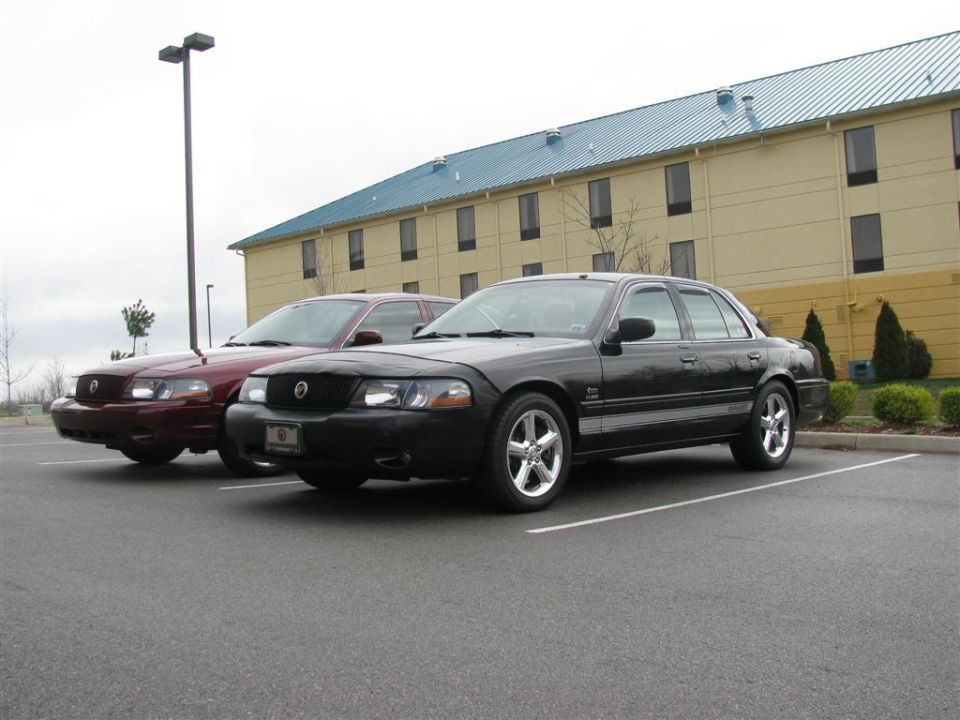 Black 2003 Mercury Marauder parked in front of a maroon one, with a hotel in the background