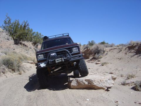 1986 Ford Bronco II - A 1986 Ford Bronco II navigates a challenging off-road course under a clear blue sky.