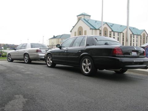 2003 Mercury Marauder - Two Mercury Marauders, one black and one silver, are parked side-by-side in front of a hotel.