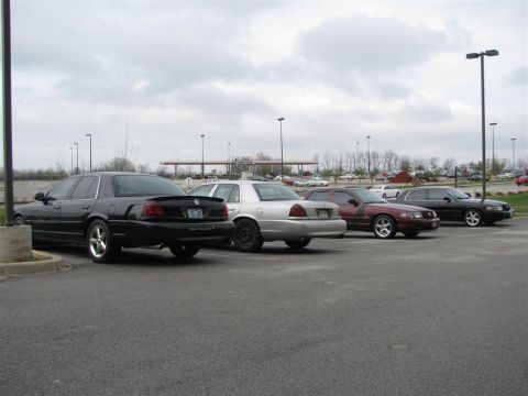 2003 Mercury Marauder - A line of sedans, including a black 2003 Mercury Marauder, are parked in an outdoor lot under a cloudy sky.