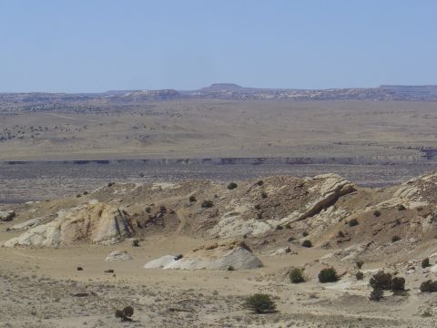 1986 Ford Bronco II - A lone SUV navigates a desert landscape with mesas in the distance.