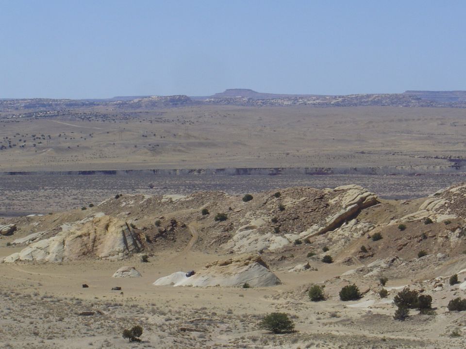 SUV driving on rocky desert terrain under a clear blue sky