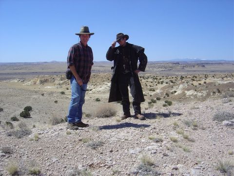 1986 Ford Bronco II - Two men dressed in western wear pose on a desolate, arid hillside with mountains in the distance.