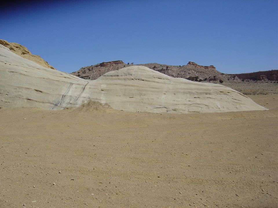 Desert landscape with layered rock formations under a clear blue sky