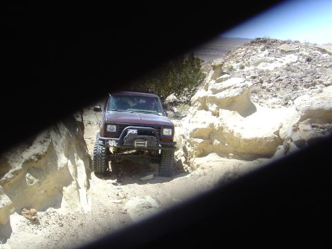 1986 Ford Bronco II - This 1986 Ford Bronco II navigates a narrow, rocky off-road path under a clear blue sky.