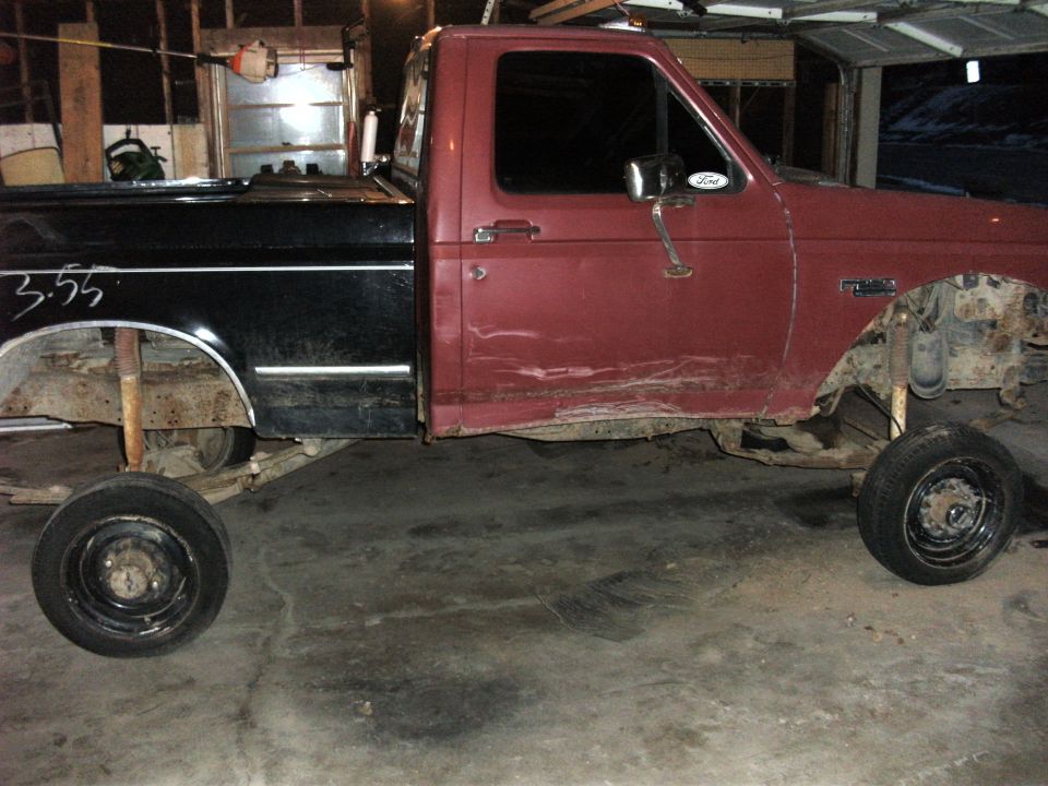 1992 Ford F-250 truck chassis with black bed and red cab, missing front wheels