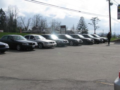 2003 Mercury Marauder - A row of sedans are parked in an outdoor lot under a cloudy sky.