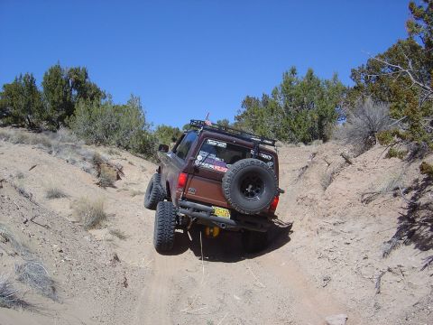 1986 Ford Bronco II - This SUV navigates a steep, dusty incline with sparse vegetation under a clear blue sky.