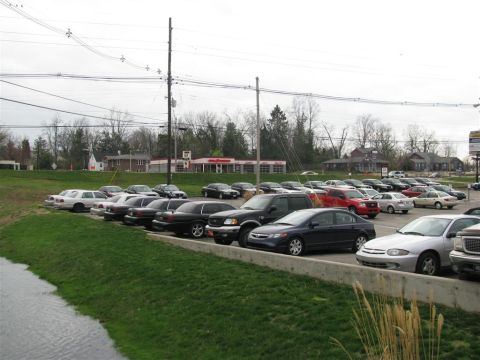 2003 Mercury Marauder - A variety of vehicles are parked in a lot, with a dark sedan and a silver sedan prominently displayed in the foreground.