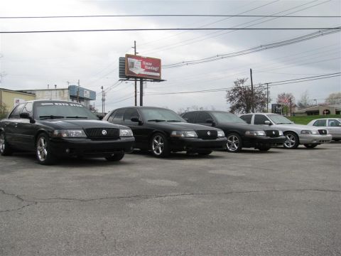 2003 Mercury Marauder - A line of Mercury sedans, likely Grand Marquis, are parked outdoors under an overcast sky.