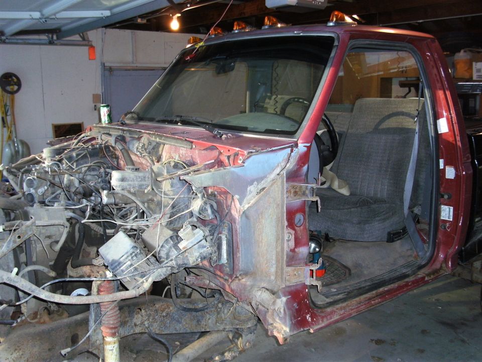 Red pickup truck with front end disassembled, engine compartment exposed, interior visible
