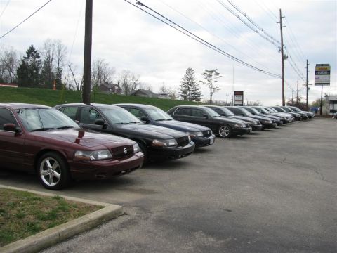 2003 Mercury Marauder - A row of sedans, including a maroon one, are parked in a lot under an overcast sky.