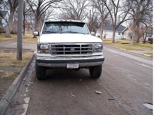 White 1992 Ford F-250 parked on a wet street, front view. The grille and headlights are visible