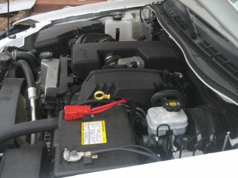 1996 Ford Thunderbird - Close-up view of a vehicle's engine bay, showing the battery, hoses, and fluid reservoirs.