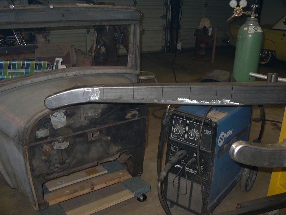 Stripped Ford Model A body in garage with welded frame rail and Miller MIG welder