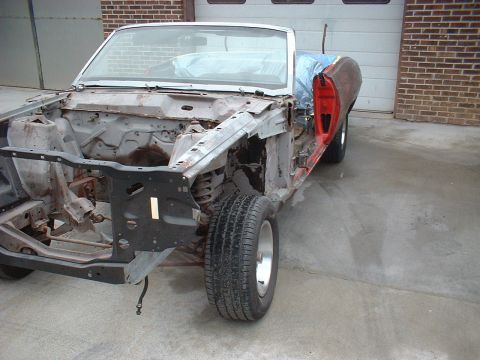 1970 Ford Torino - This 1970 Ford Torino convertible is undergoing restoration, with its front end disassembled and one red door visible.