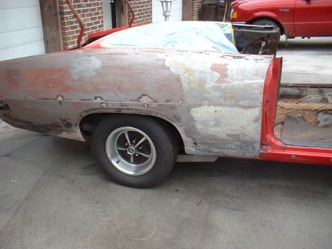 1970 Ford Torino - A 1970 Ford Torino is seen from the side, with its body in a state of repair, revealing primer and filler work.