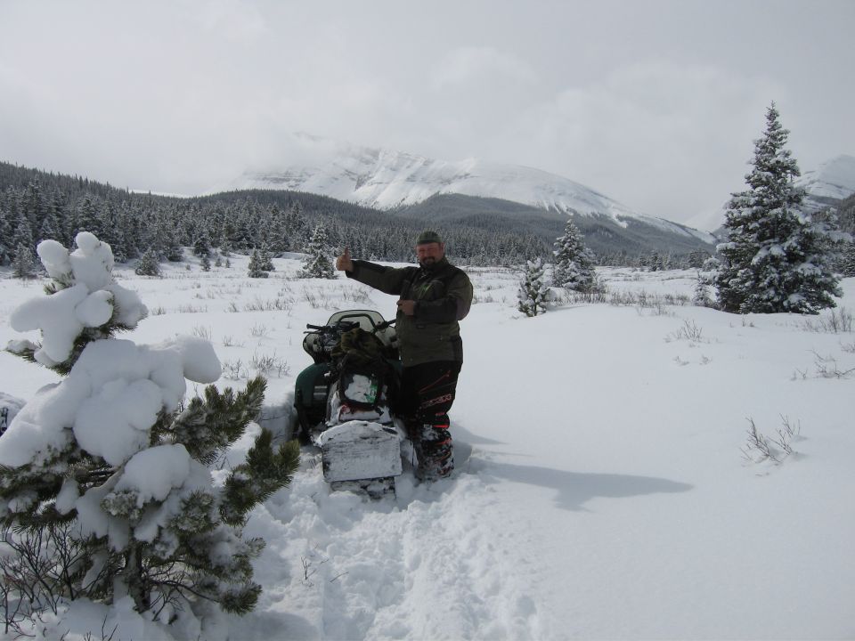 Snowmobile in a snowy landscape with a man giving a thumbs up