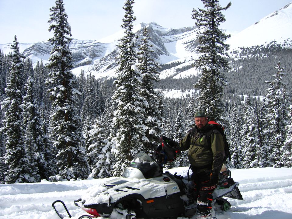 Snowmobile in a snowy mountain landscape with a man standing next to it