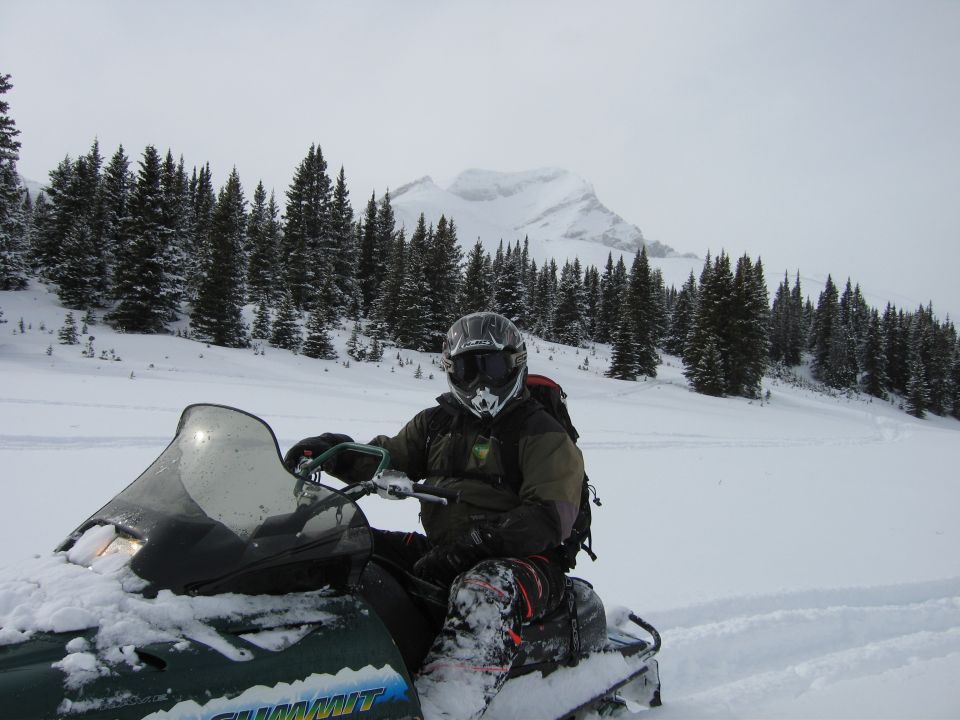 Snowmobile in a snowy landscape with pine trees and mountains