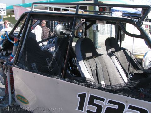 1990 Ford Bronco - Close view of buggy number 1522 interior showing the roll cage, mesh netting, and gray racing bucket seats.