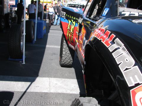 1990 Ford Bronco - Close-up of a black desert race truck's fender with General Tire branding, parked near a tire display at an outdoor event.