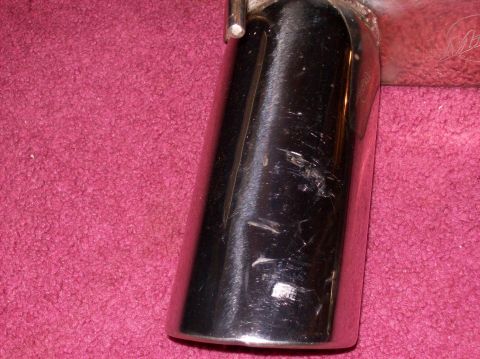 2007 Ford Mustang - A close-up view of a chrome exhaust tip, showing significant scratches and scuffs on its surface.