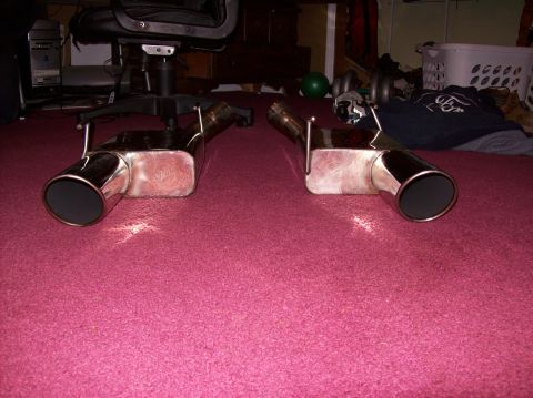 2007 Ford Mustang - Two chrome exhaust mufflers with black tips are displayed on a pink carpet.