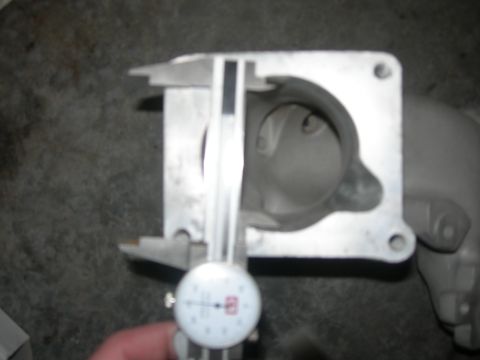 1984 Ford Bronco - A caliper measures the opening of a throttle body, likely for performance tuning or replacement.