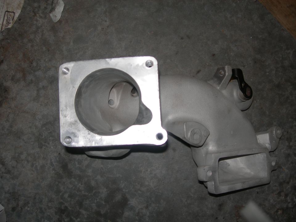 Aluminum throttle body bolted to a cast iron intake manifold with a black lever