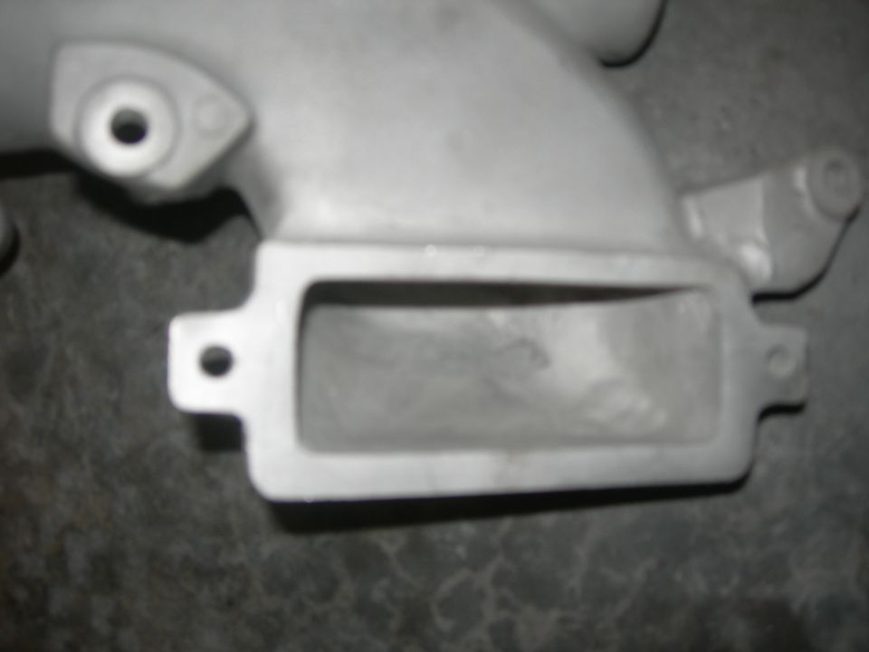 Close-up of a metal intake manifold part with a rectangular opening