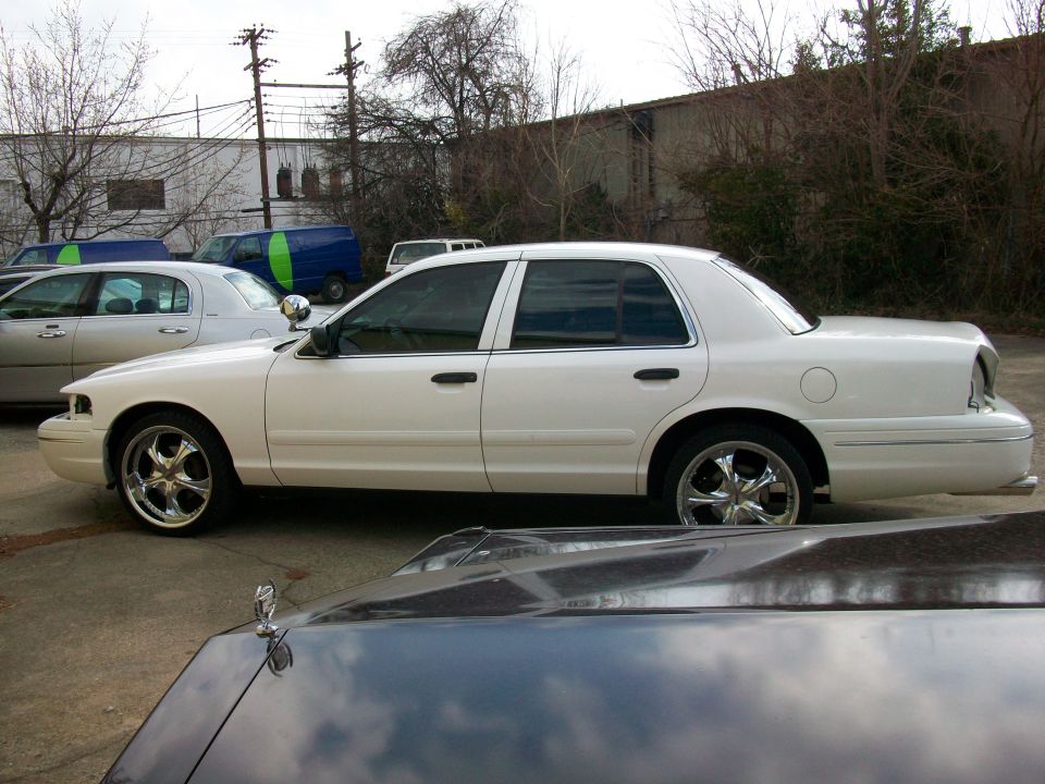 White 2003 Ford Crown Victoria parked next to another car. Chrome wheels visible